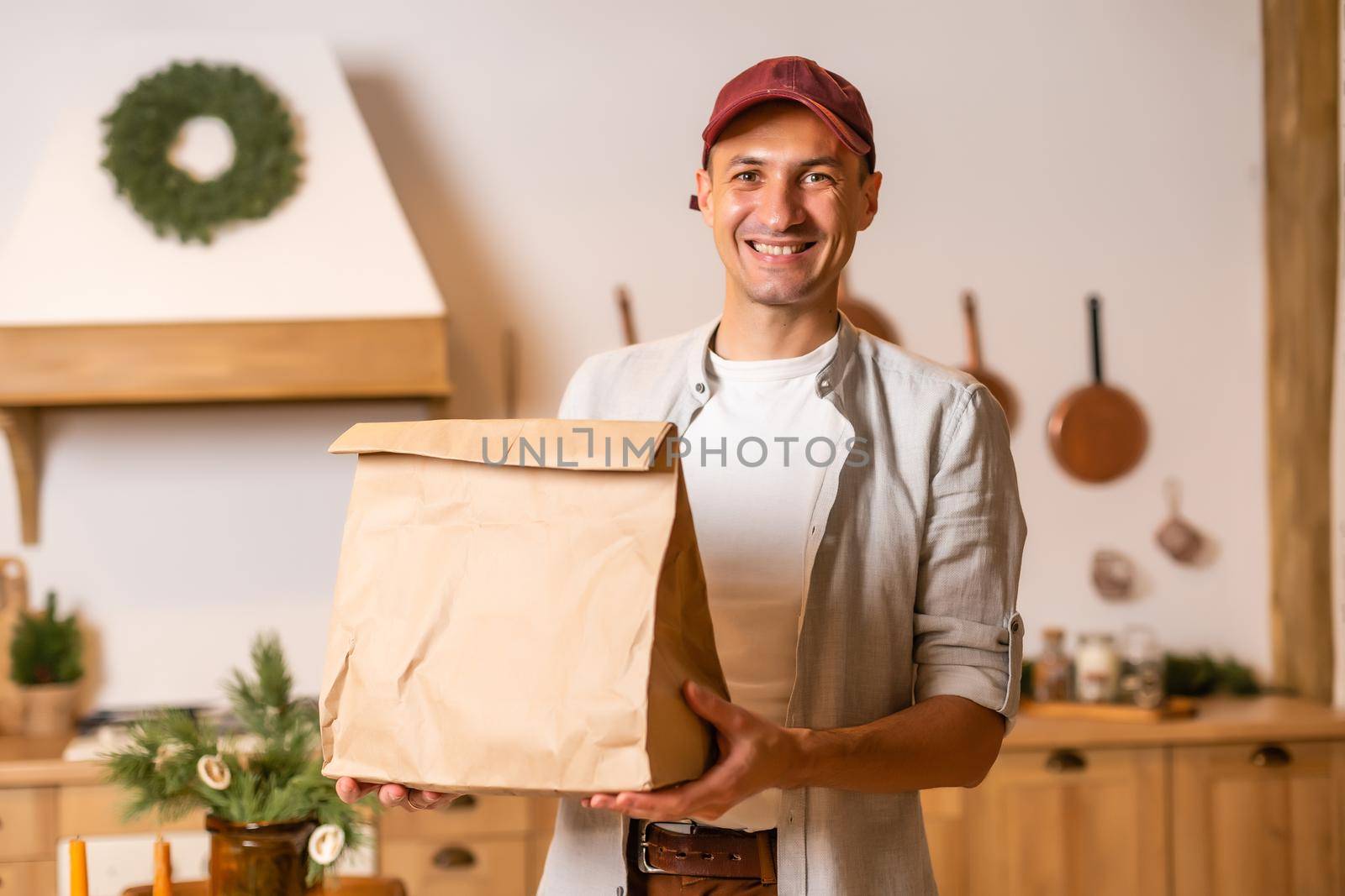a delivery man with a package of food stands in a Christmas interior