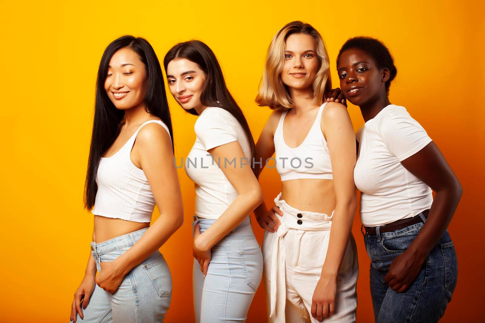 diverse multi nation girls group, teenage friends company cheerful having fun, happy smiling, cute posing on yellow background, lifestyle people concept, african-american, asian and caucasian close up