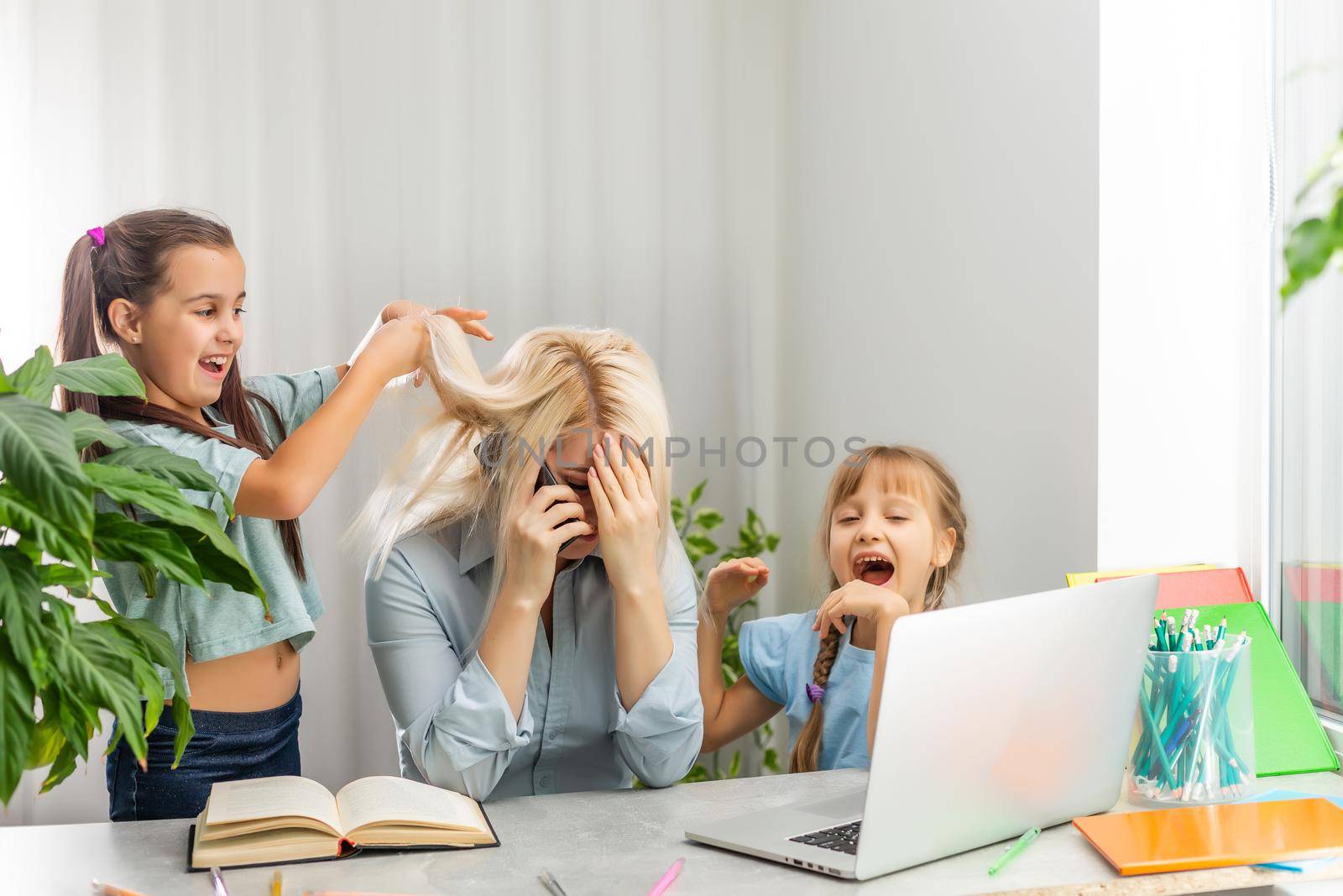 A young mother with two children works from home on a computer. Fatigue Lifestyle Housewife Freelance. tired mother and two little daughters