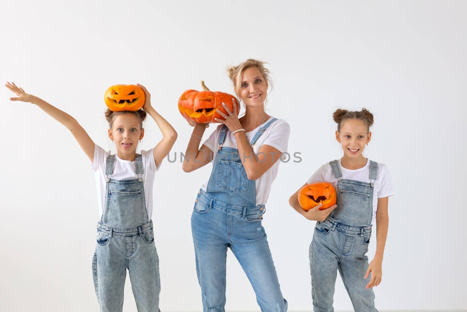 Happy halloween and holidays concept - A mother and her daughters with pumpkins. Happy family preparing for Halloween