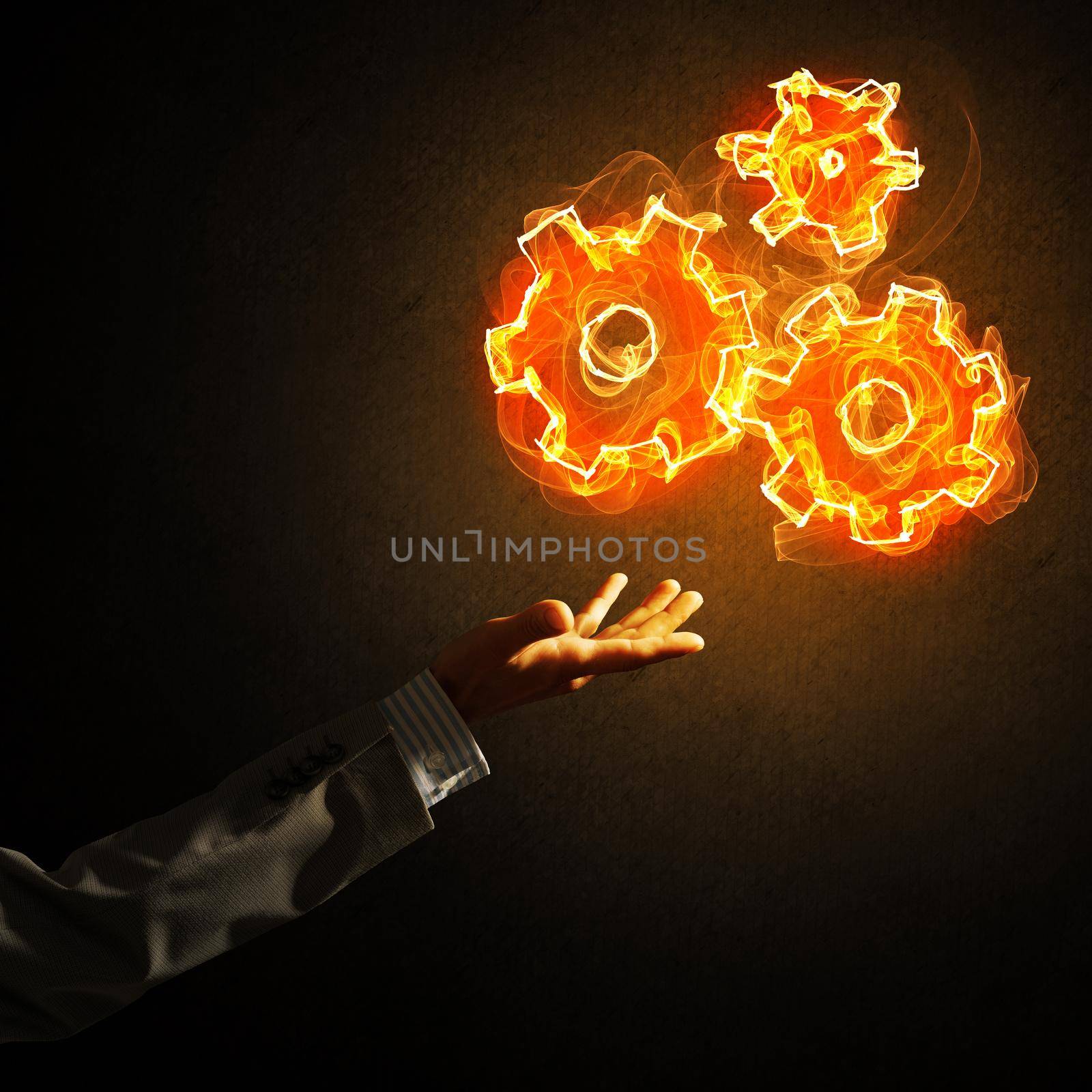 Hand of businessman pointing fire gear mechanism on dark background