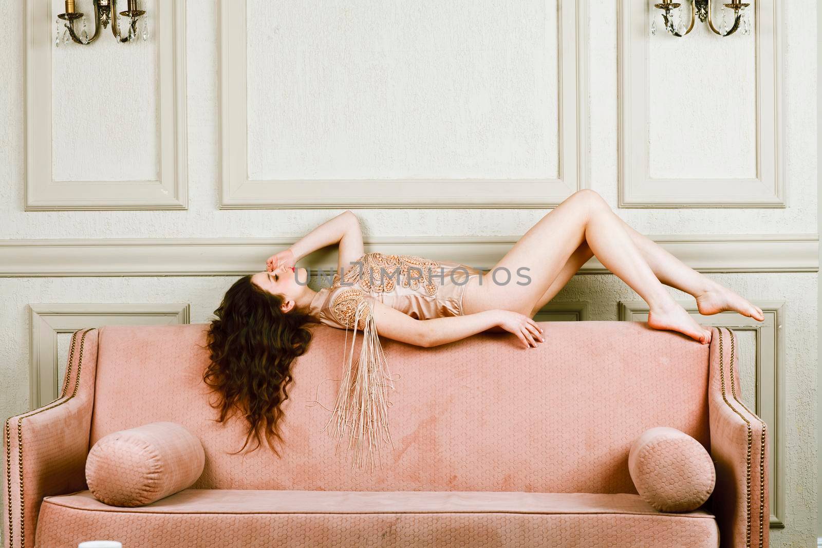 young pretty brunette girl in fashion dress on sofa posing in luxury rich home interior, lifestyle modern people concept close up