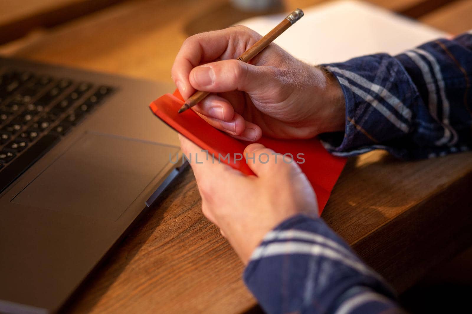 Cropped image of casual business man or freelancer planning his work on notebook, working on laptop computer with smart phone, cup of coffee on table at coffee shop or home office, working from cafe concept