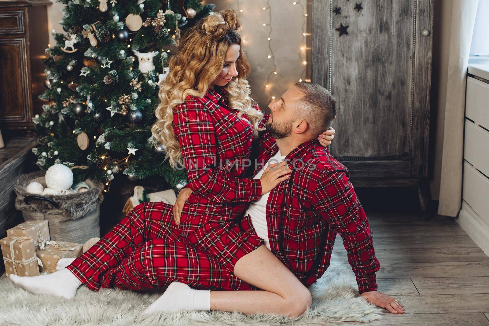 Happy young couple in pajamas sitting on the floor with a Christmas tree in the background