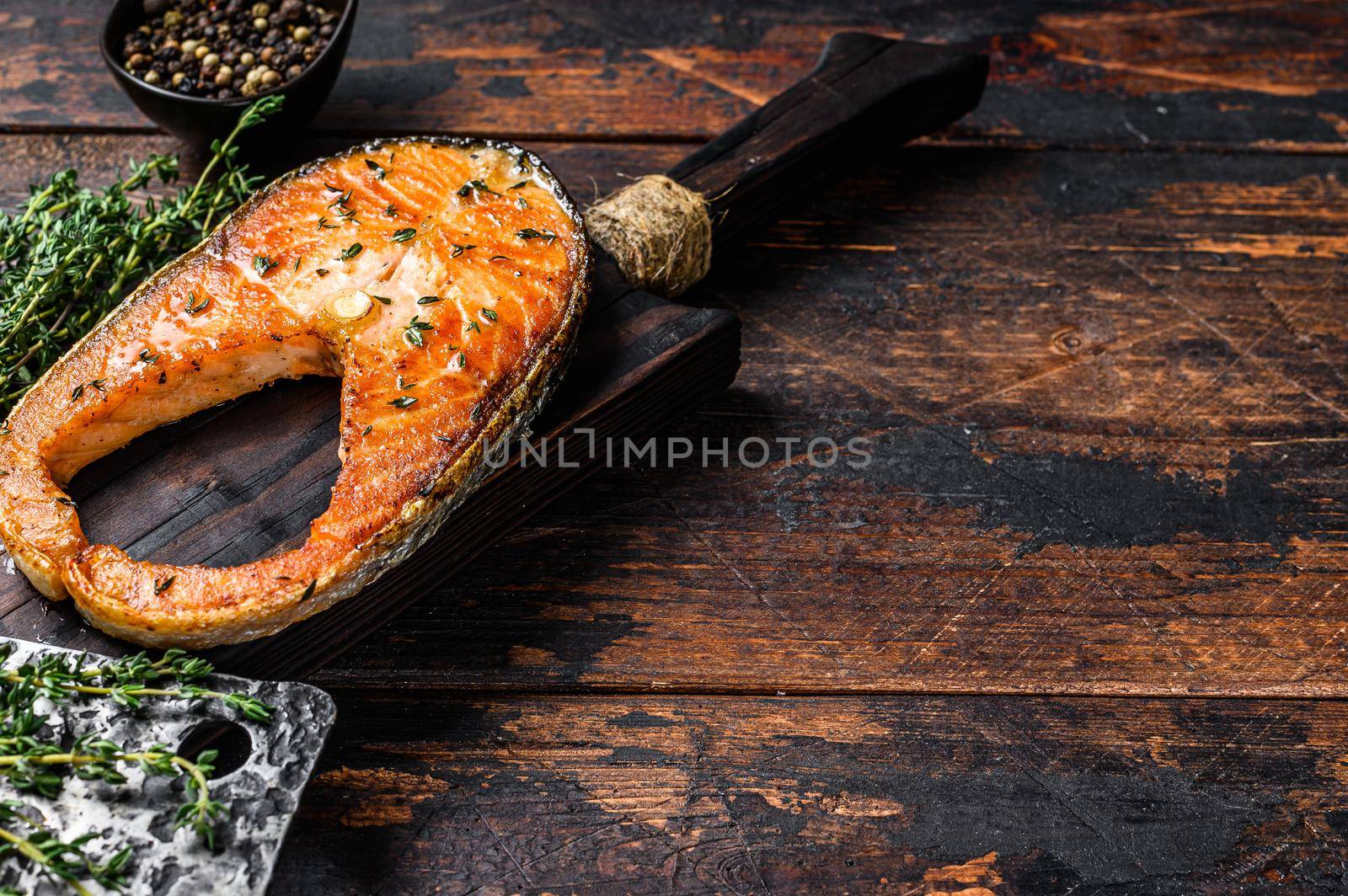 Fried trout fillet steak with pepper. Dark wooden background. Top view. Copy space.