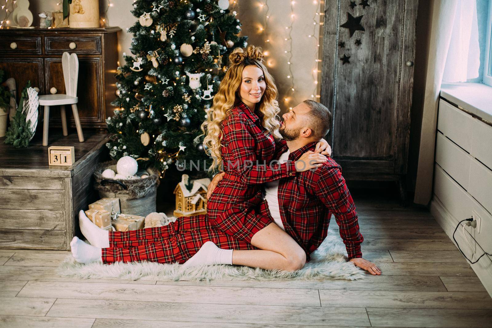 Beautiful couple in love relaxes on the floor in the living room together by StudioLucky