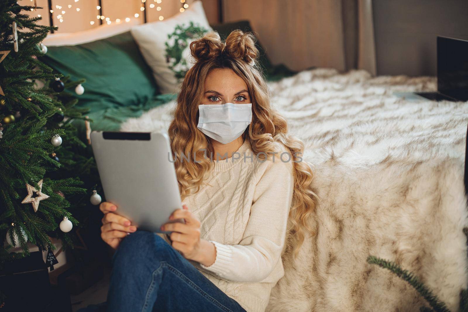 Pretty lady holding tablet while sitting on the floor in her bedroom by StudioLucky