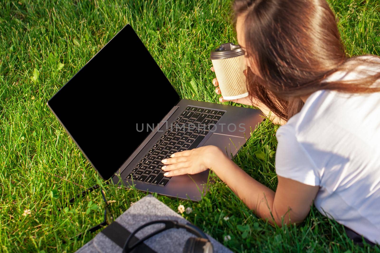 Close up hands on keyboard. Woman working on laptop pc computer with blank black empty screen to copy space in park on green grass sunshine lawn outdoors. Mobile Office. Freelance business concept