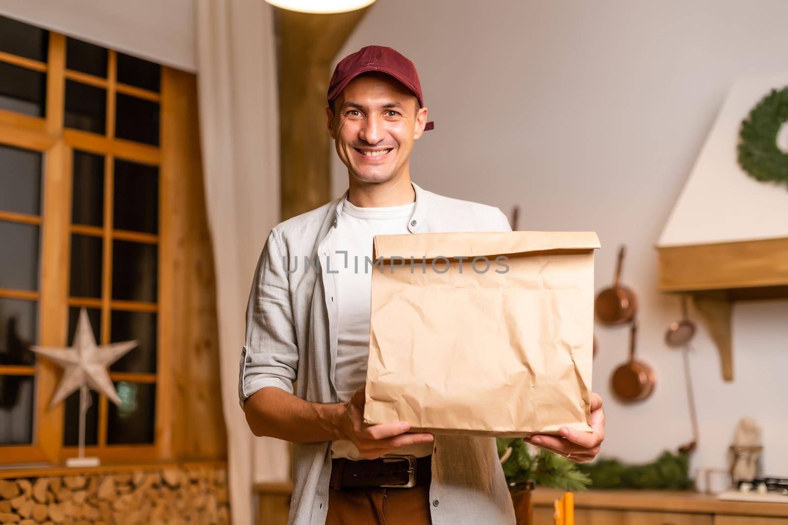 a delivery man with a package of food stands in a Christmas interior