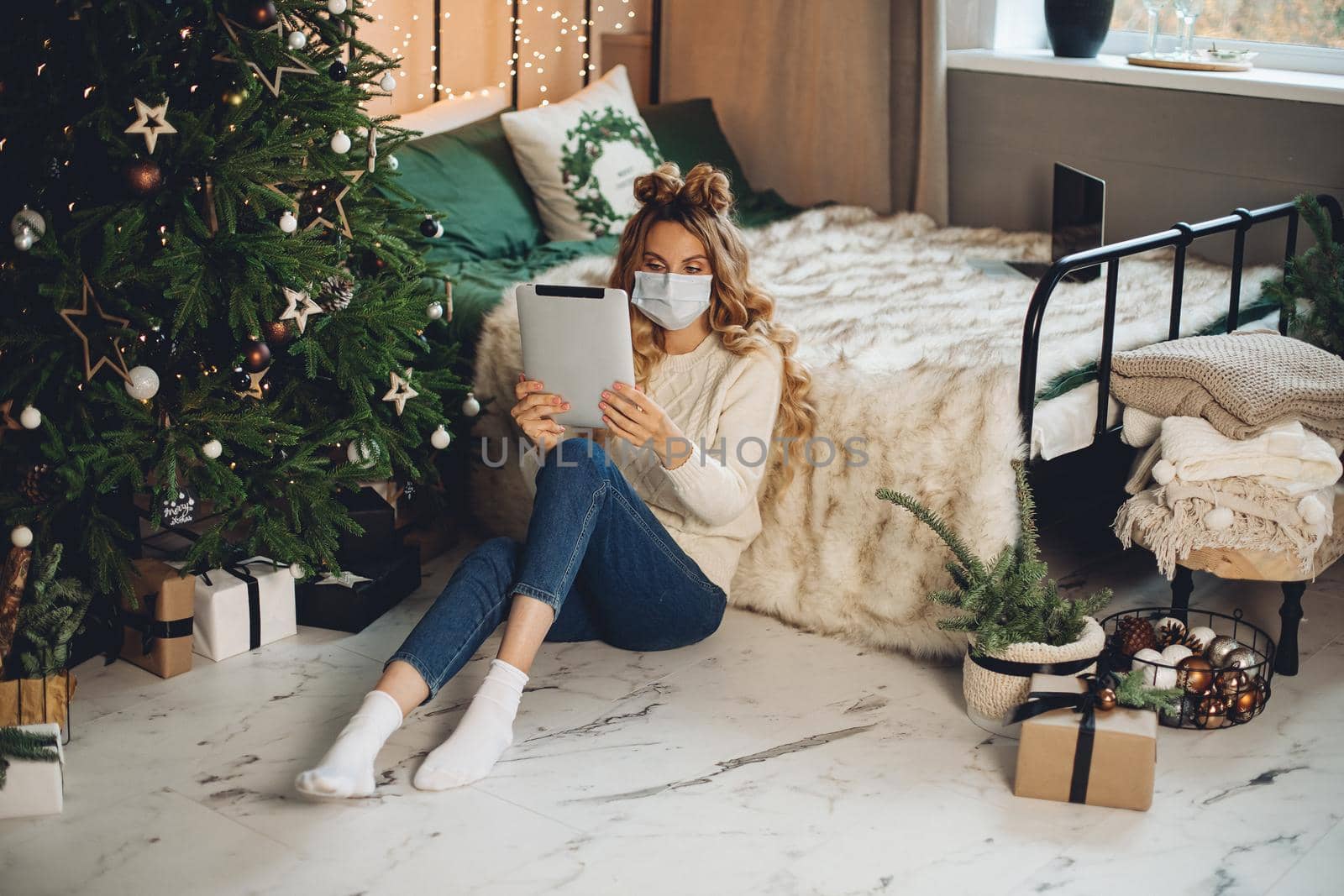 Girl in face mask using tablet at xmas. by StudioLucky