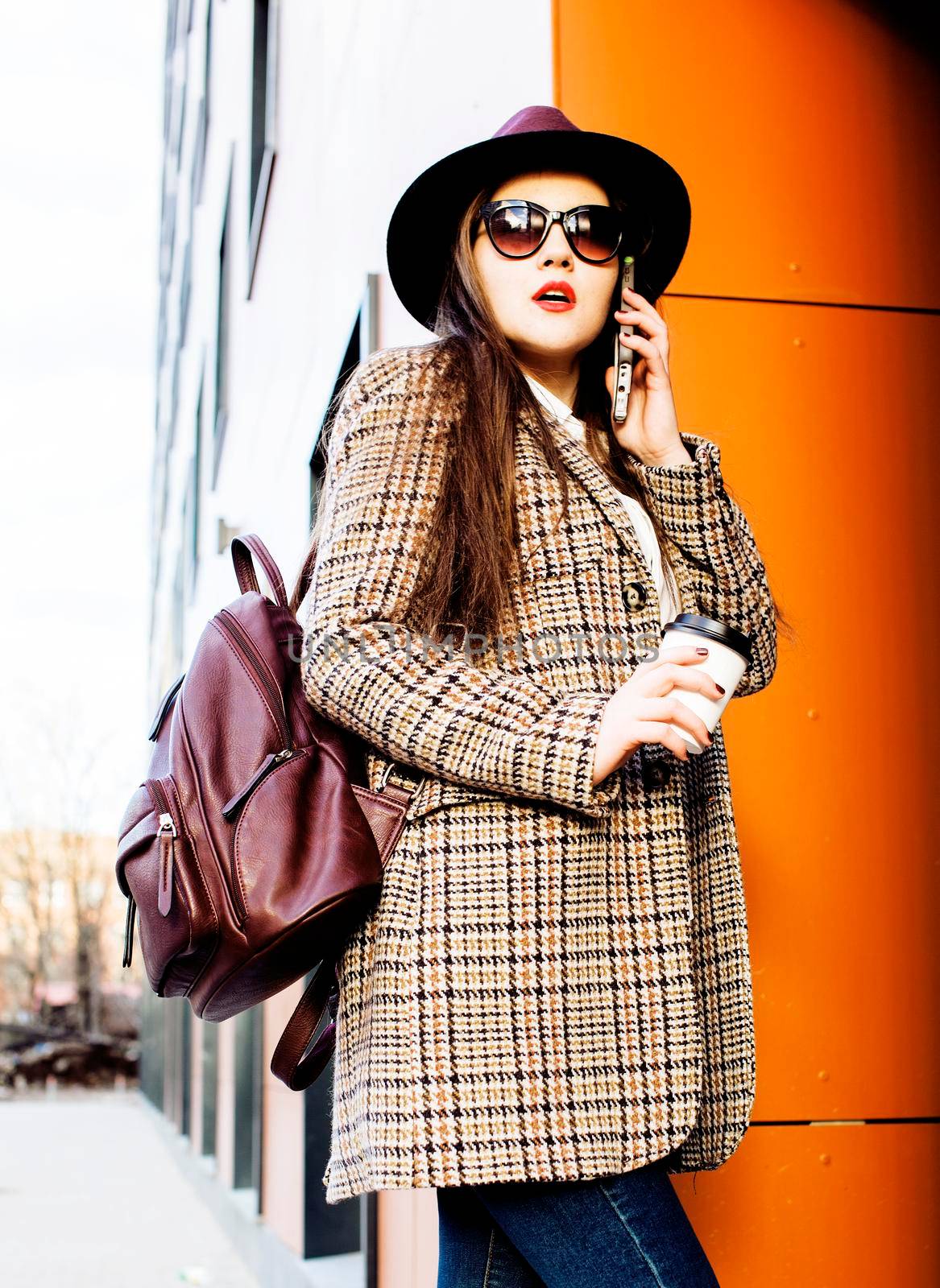 young pretty brunette business woman posing against modern building in hat holding coffee, lifestyle people concept by JordanJ