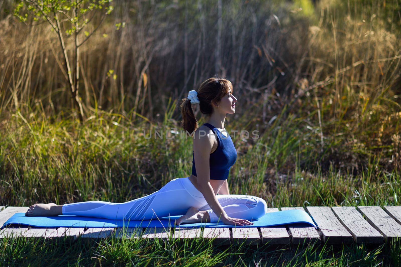 Young woman doing yoga in nature. Female wearing sport clothes.