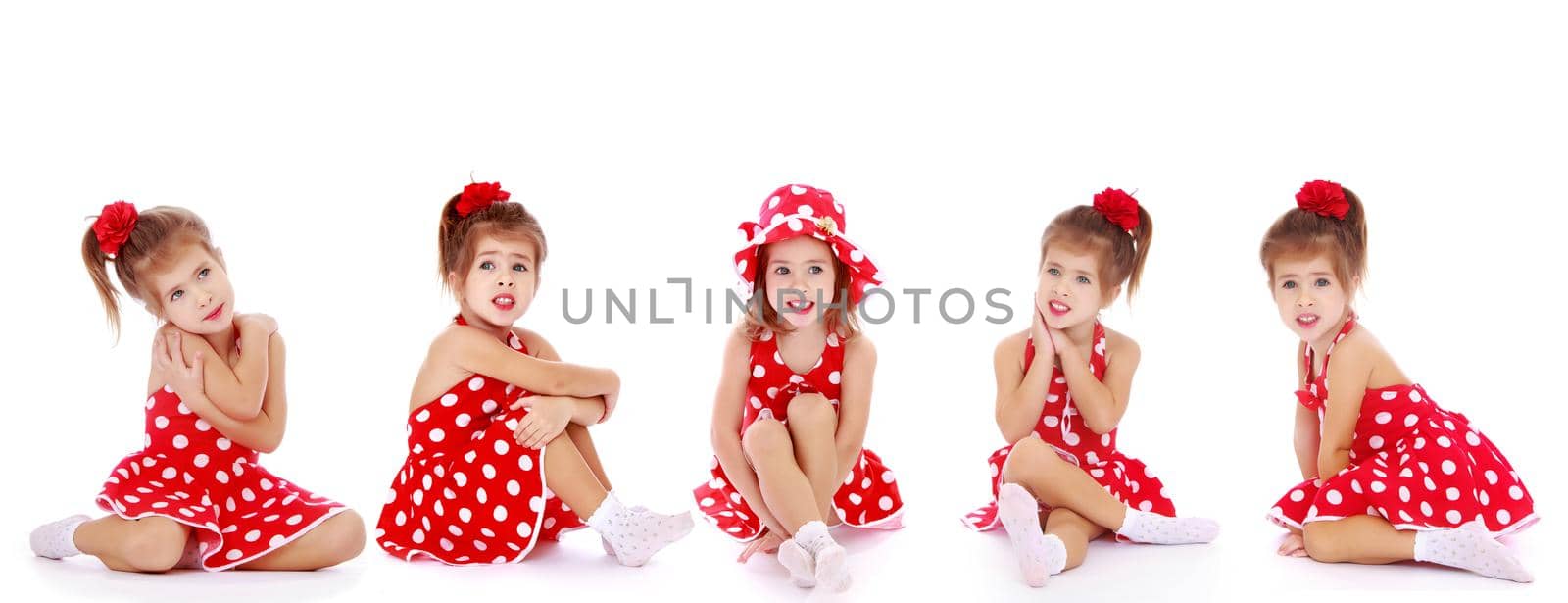 Beautiful little girl is sitting on the floor in the studio. The concept of a happy childhood, beauty and fashion. Isolated on white background.