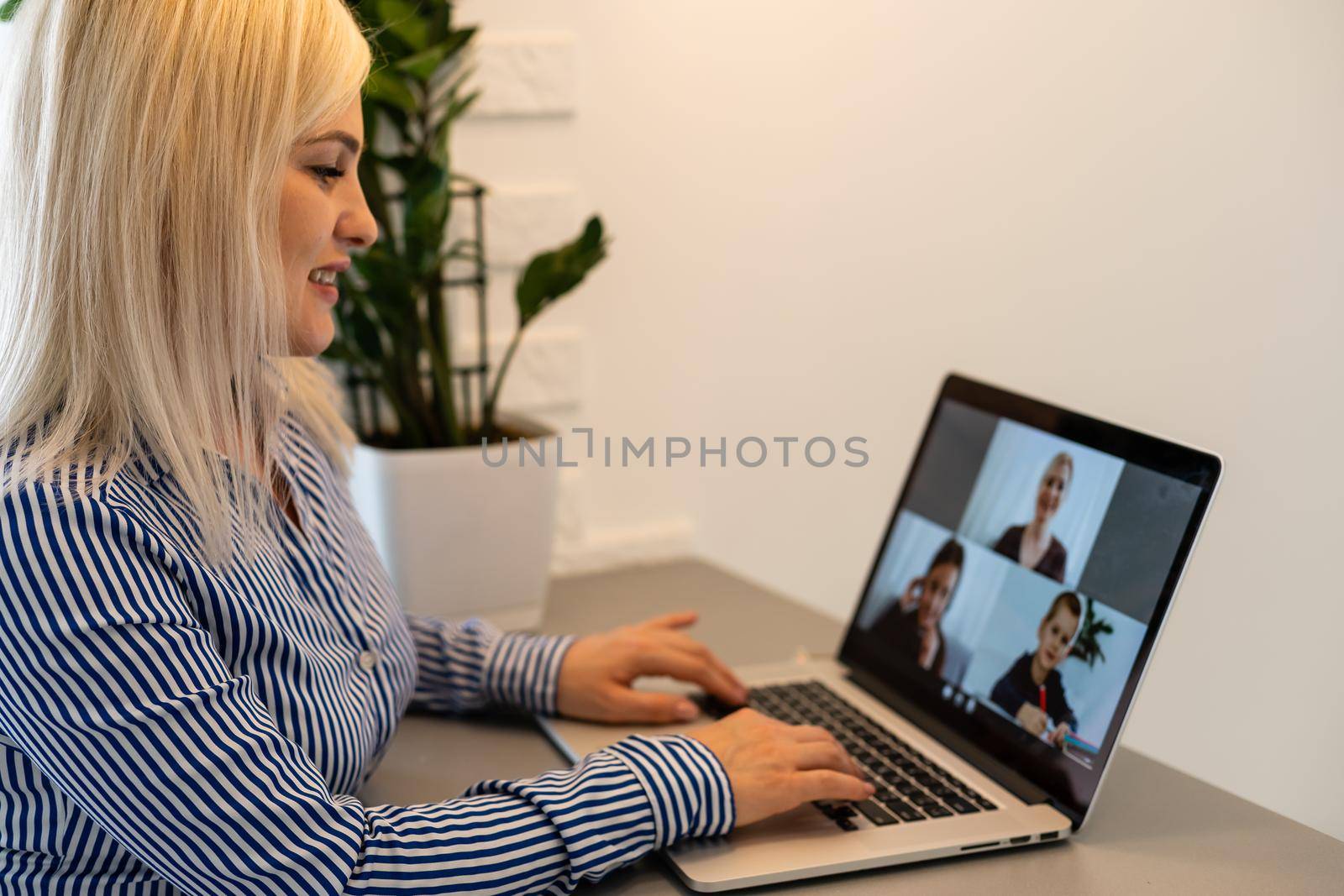 Back view of business woman talking to her colleagues about plan in video conference. Multiethnic business team using laptop for a online meeting in video call. Group of people smart working from home by Andelov13
