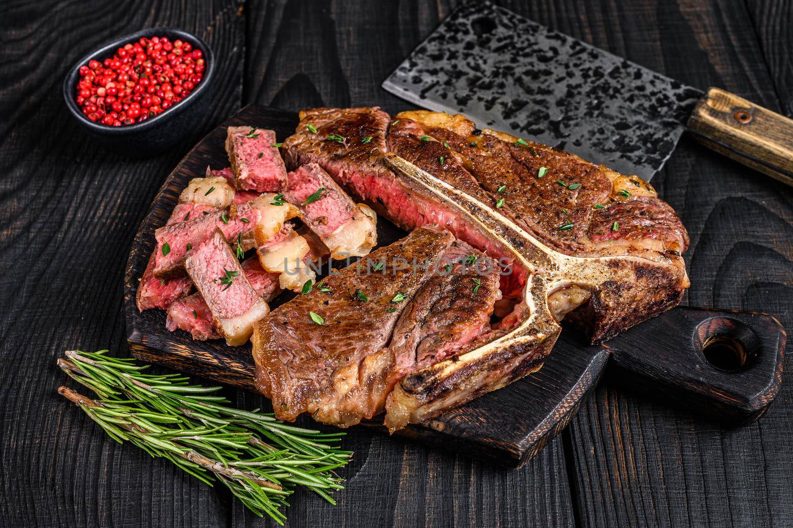 Sliced and roast T-bone or porterhouse beef meat Steak for steakhouse menu. Black wooden background. Top view.