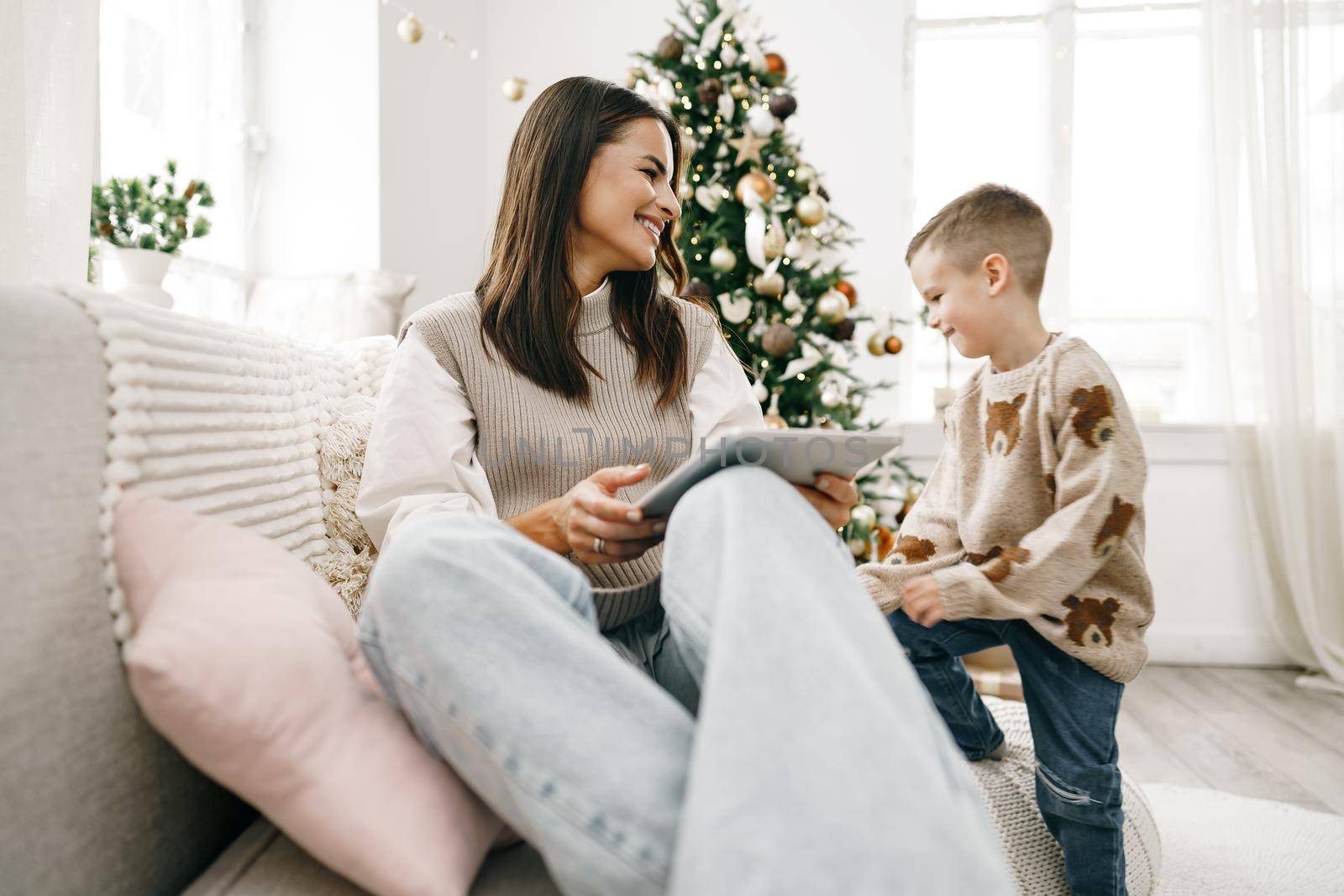Portrait of a smiling young woman with her son using digital tablet on winter holidays at home