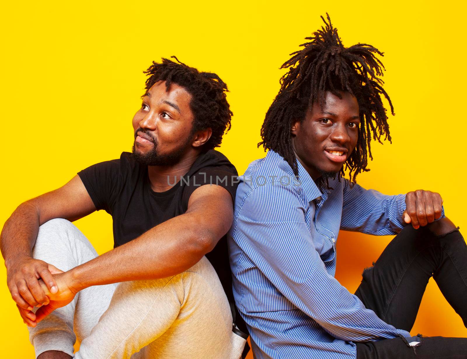 two african american guys posing cheerful together on yellow background, lifestyle people concept close up