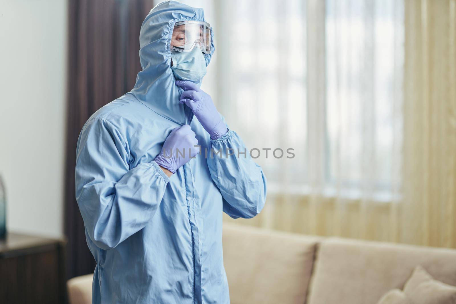 Waist up of worker standing in hotel apartments in protective clothing. Coronavirus and quarantine concept
