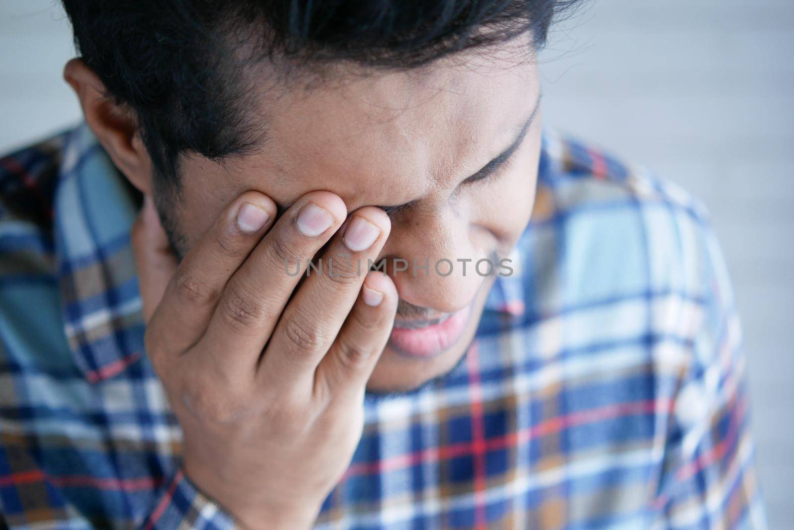 Close up of upset man suffering from strong eye pain by towfiq007