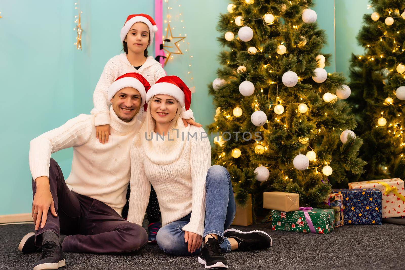 happy young family with one child holding christmas gift and smiling at camera by Andelov13