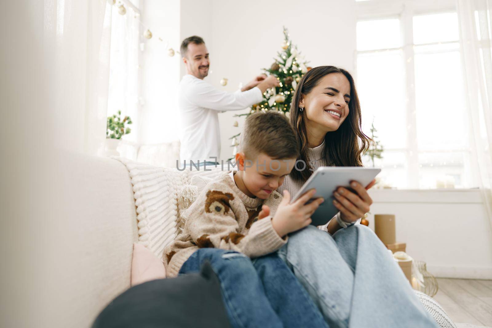 Portrait of a smiling young woman with her son using digital tablet on winter holidays by Fabrikasimf