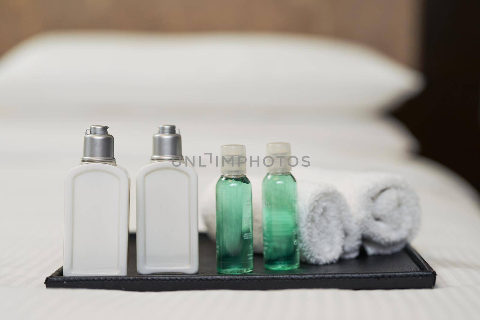 Close up of shower set in hotel on bed with pillows in the background. Hotel service concept