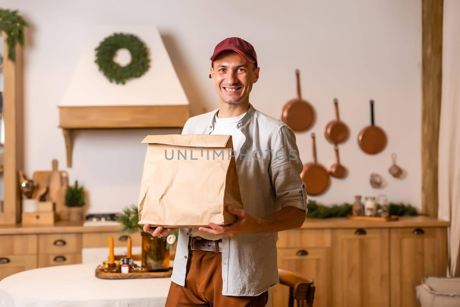 a delivery man with a package of food stands in a Christmas interior