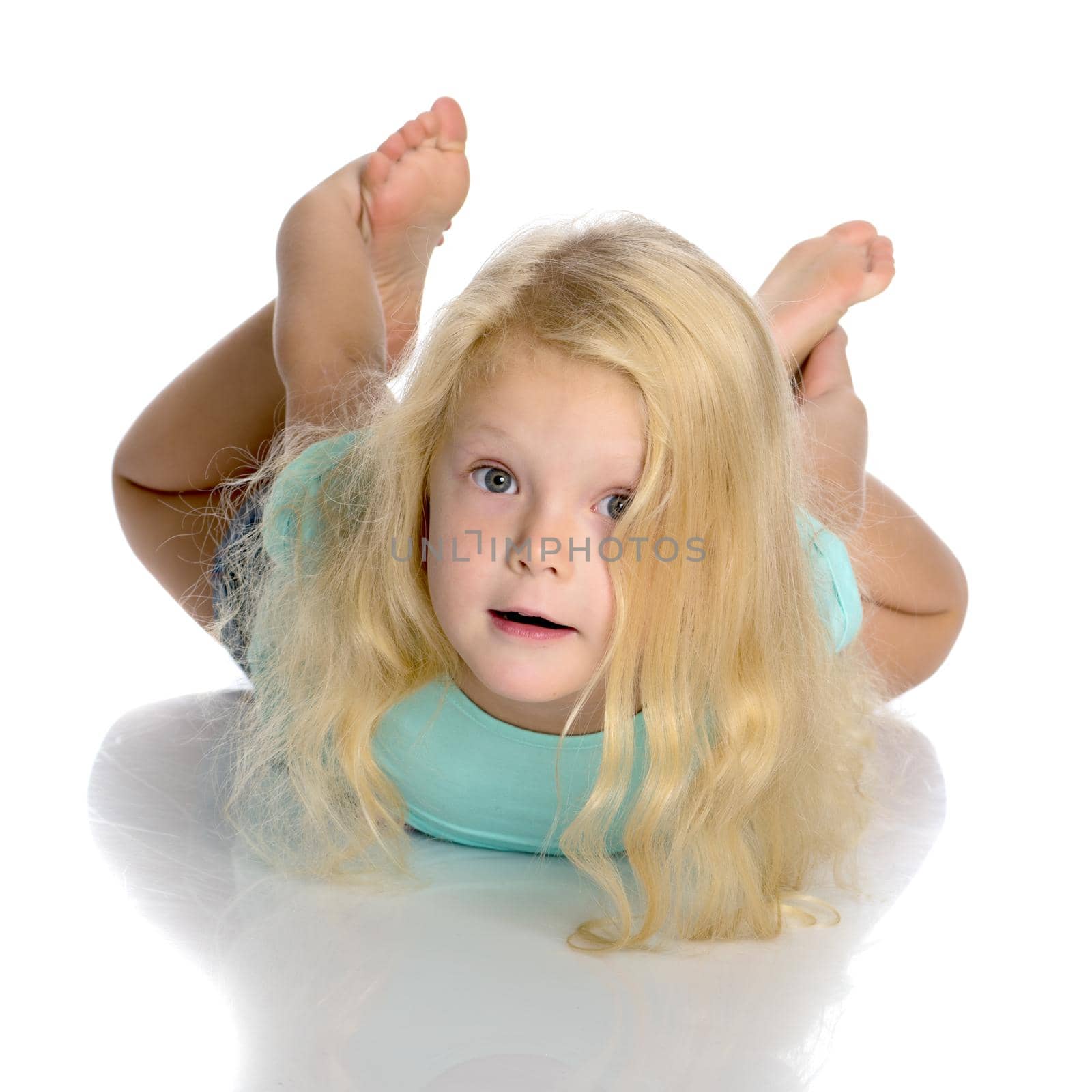 Beautiful little girl lies on the floor on a white background. The concept of a happy childhood, well-being in the family. Isolated.