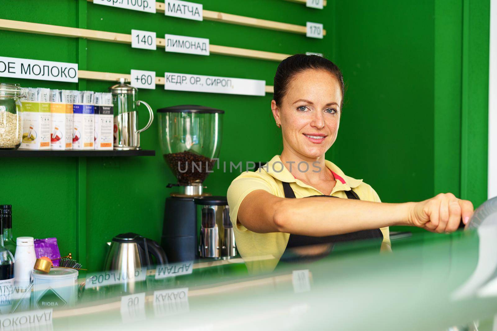 Portrait of a woman barista in coffee shop standing at counter