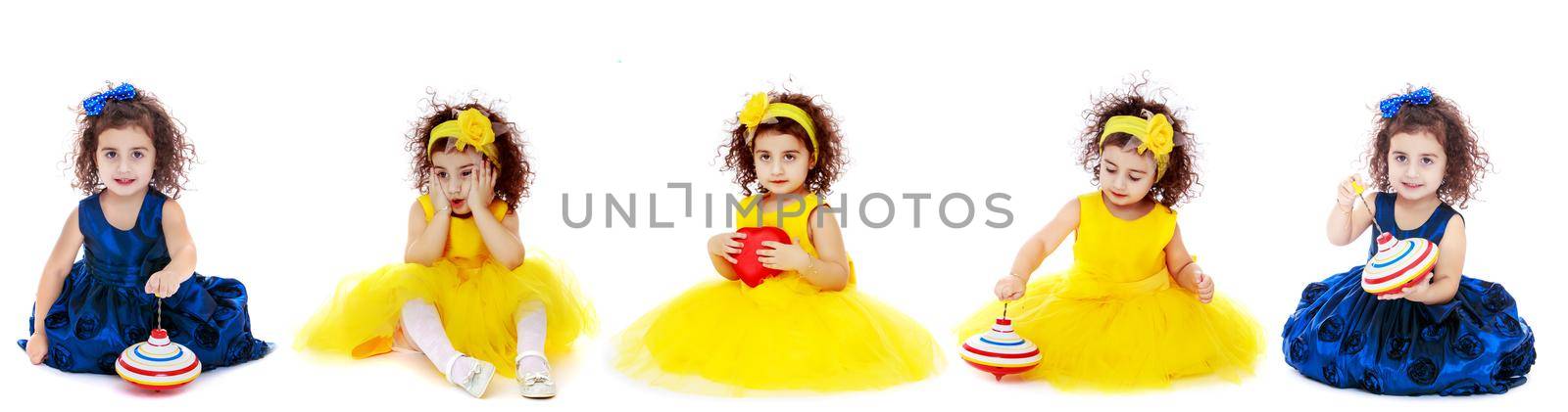 Beautiful little girl is sitting on the floor in the studio. The concept of a happy childhood, beauty and fashion. Isolated on white background.