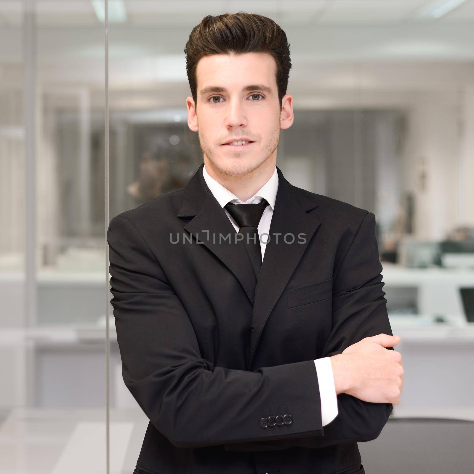 Handsome young businessman in an office by javiindy