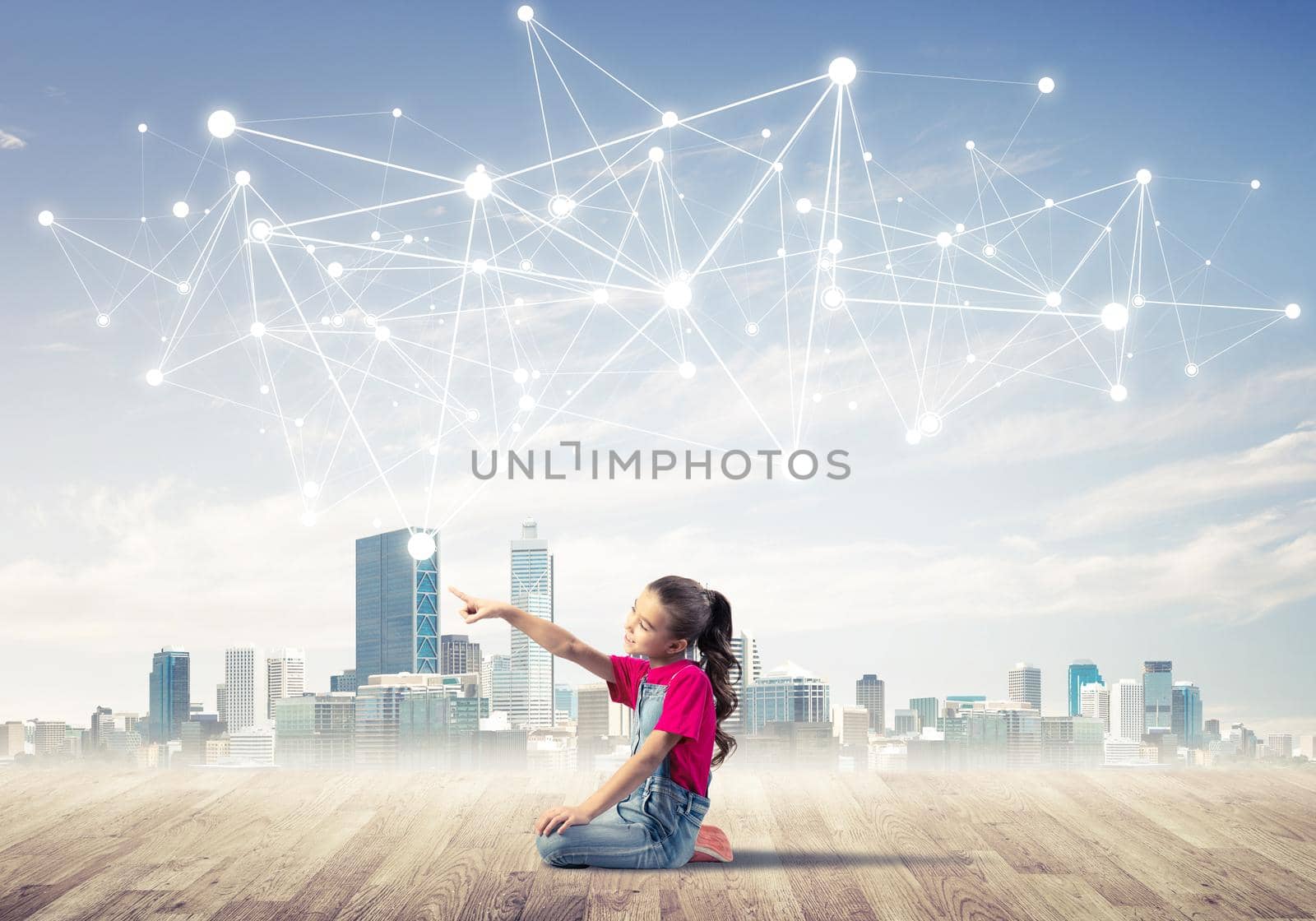 Cute kid girl sitting on wooden floor and pointing with finger