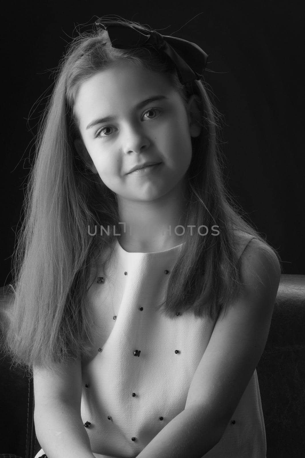 Beautiful little girl, studio portrait on a black background. The concept of children's emotions, style and fashion. Black and white photo.