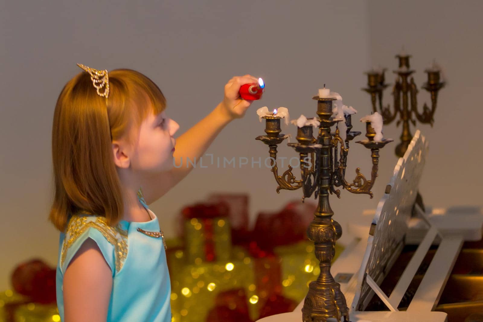 Romantic little girl lights candles on Christmas night. Family holidays concept.