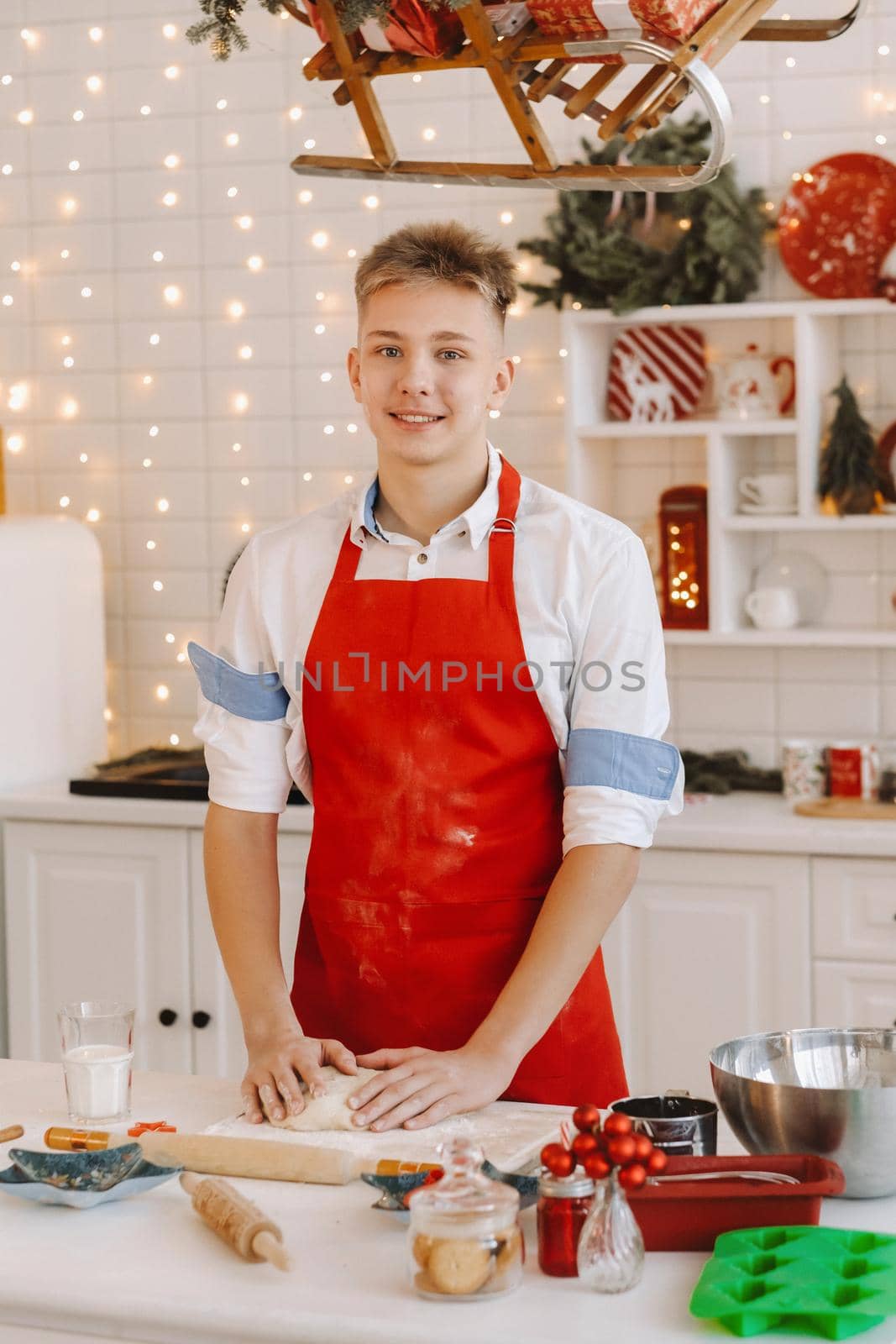 A male chef prepares dough in the Christmas kitchen before the New year by Lobachad