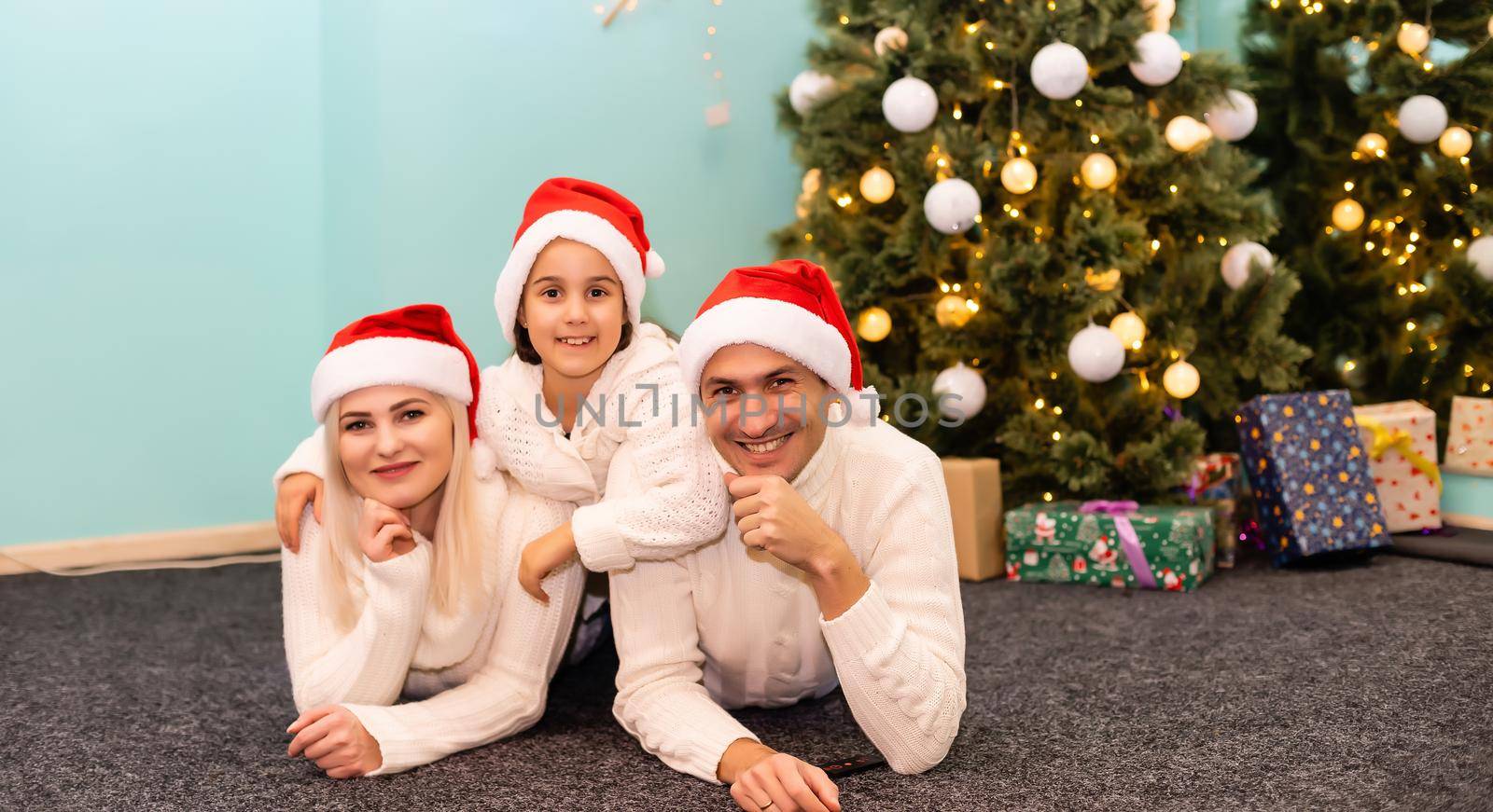 happy young family with one child holding christmas gift and smiling at camera by Andelov13