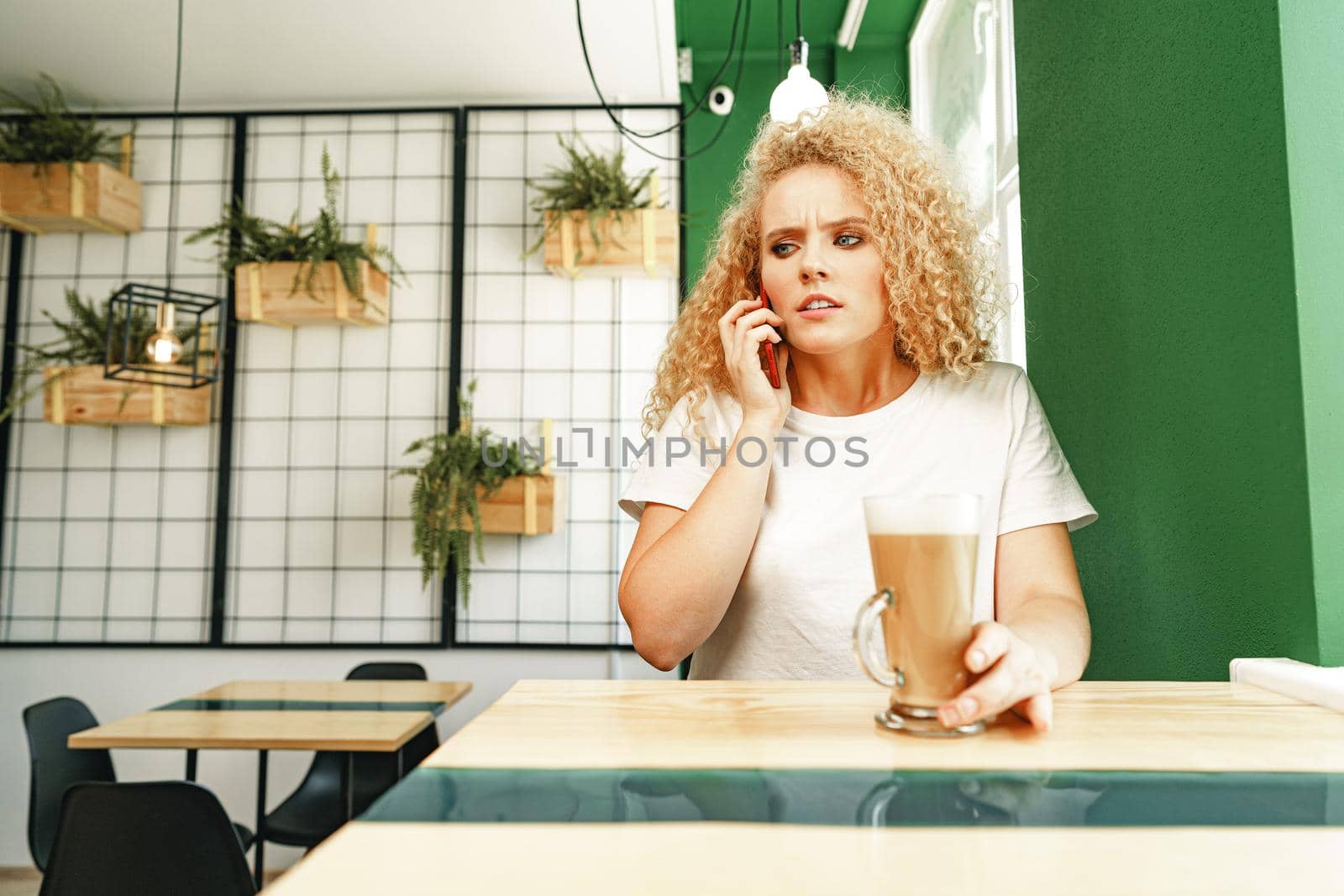 Young beautiful woman talking on the phone in cafeteria close up