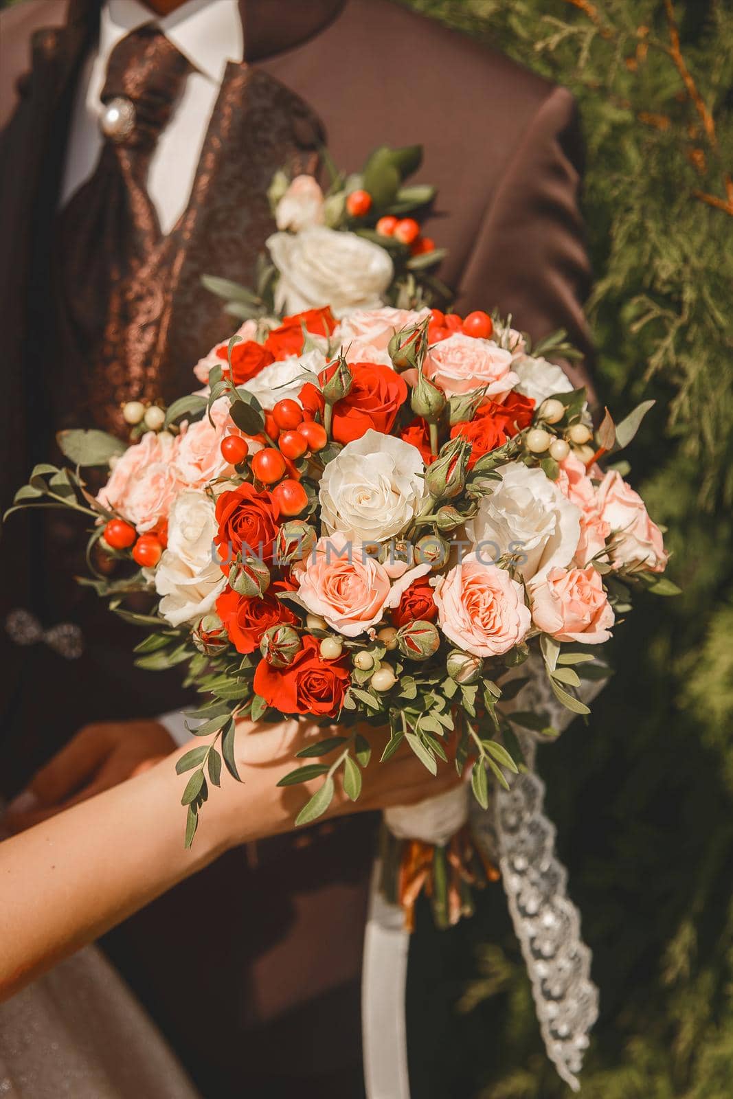 The bride holds in her hand a wedding decorative bouquet of live flowers of red and white roses by AYDO8