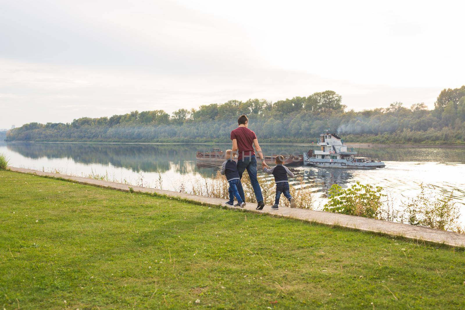 Childhood, family and fatherhood concept - Dad and sons walking together.