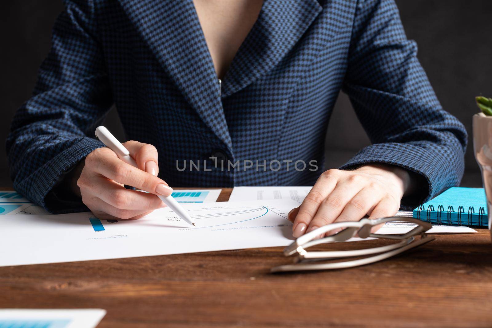 Investment manager analyze financial diagram at wooden desk. Close up woman hand with pen. Strategy planning and banking. Analyst working at workplace in office. Business accounting and management.