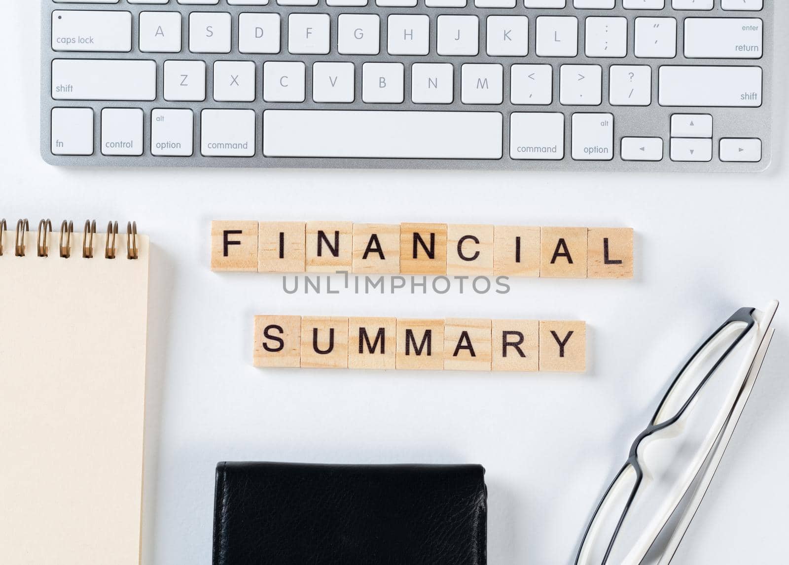 Financial summary concept with letters on wooden cubes. Still life of office workplace with supplies. Flat lay white surface with computer keyboard and notepad. Budget planning, audit and accounting.