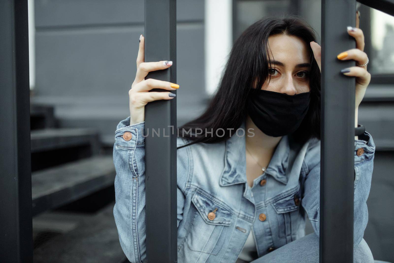 Sad teenager girl in medical mask behind bars. Schools are quarantined due to illness, epidemics. Coronavirus pandemic. Covid 19 by UcheaD