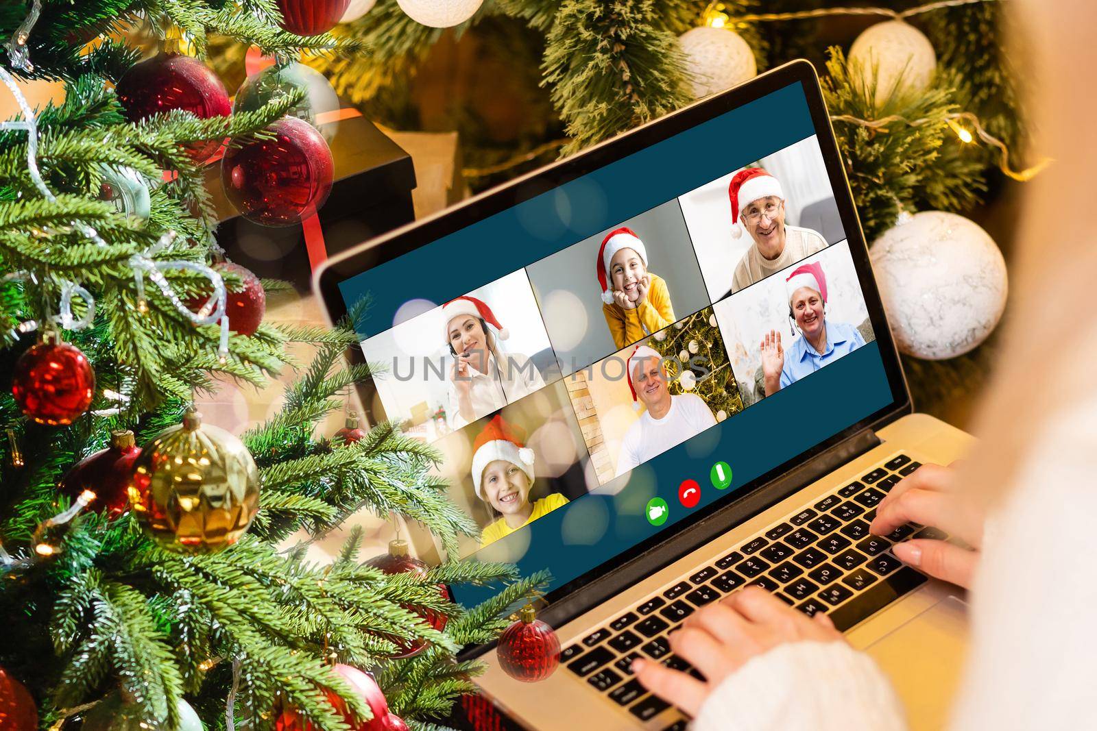 Christmas greetings online. a woman in a white sweater and red Santa hat uses a laptop to make video calls to friends, parents, and for online shopping by Andelov13