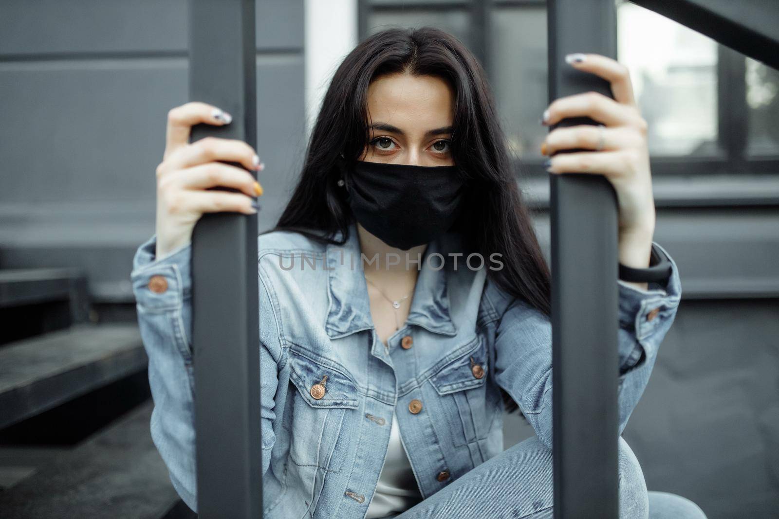 Sad teenager girl in medical mask behind bars. Schools are quarantined due to illness, epidemics. Coronavirus pandemic. Covid 19 by UcheaD