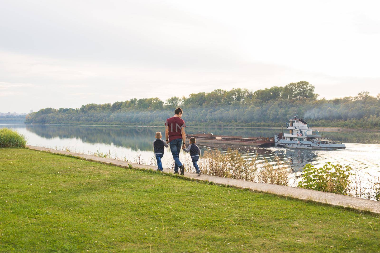 Childhood, family and fatherhood concept - Dad and sons walking together.