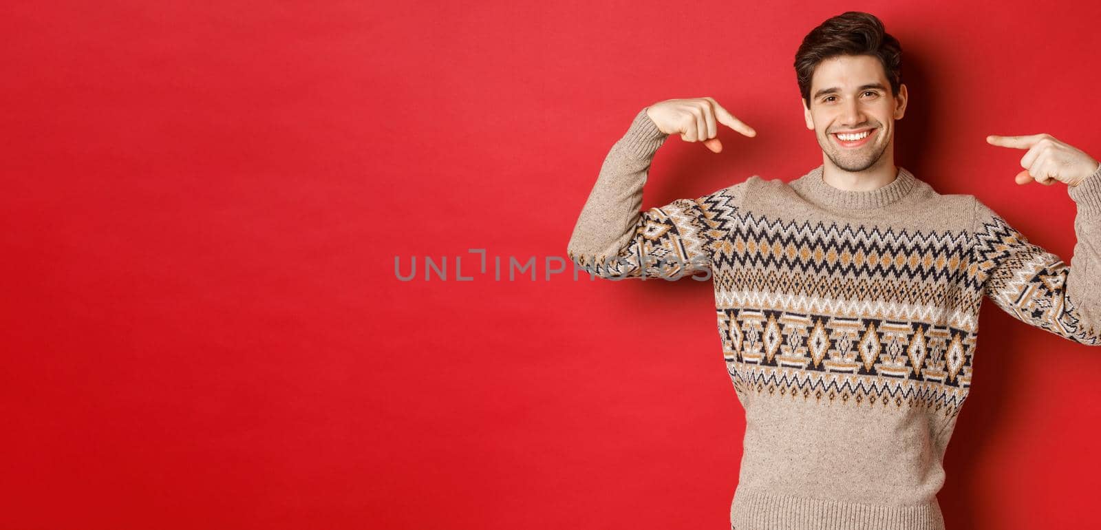 Concept of christmas celebration, winter holidays and lifestyle. Image of happy handsome man in xmas sweater pointing at himself and smiling, being secret santa, standing over red background by Benzoix