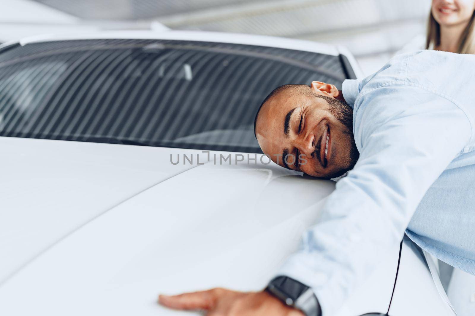 Young couple man and woman hugging their new car in a car shop close up