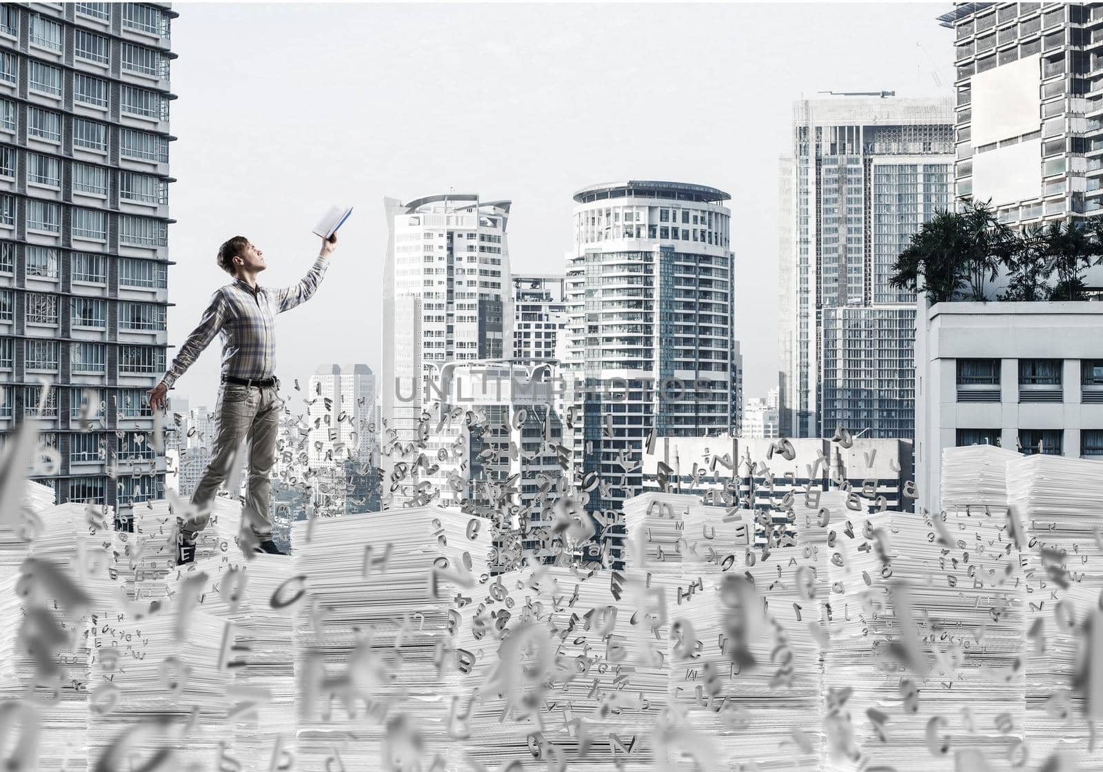 Man in casual wear keeping hand with book up while standing among flying letters with cityscape on background. Mixed media.