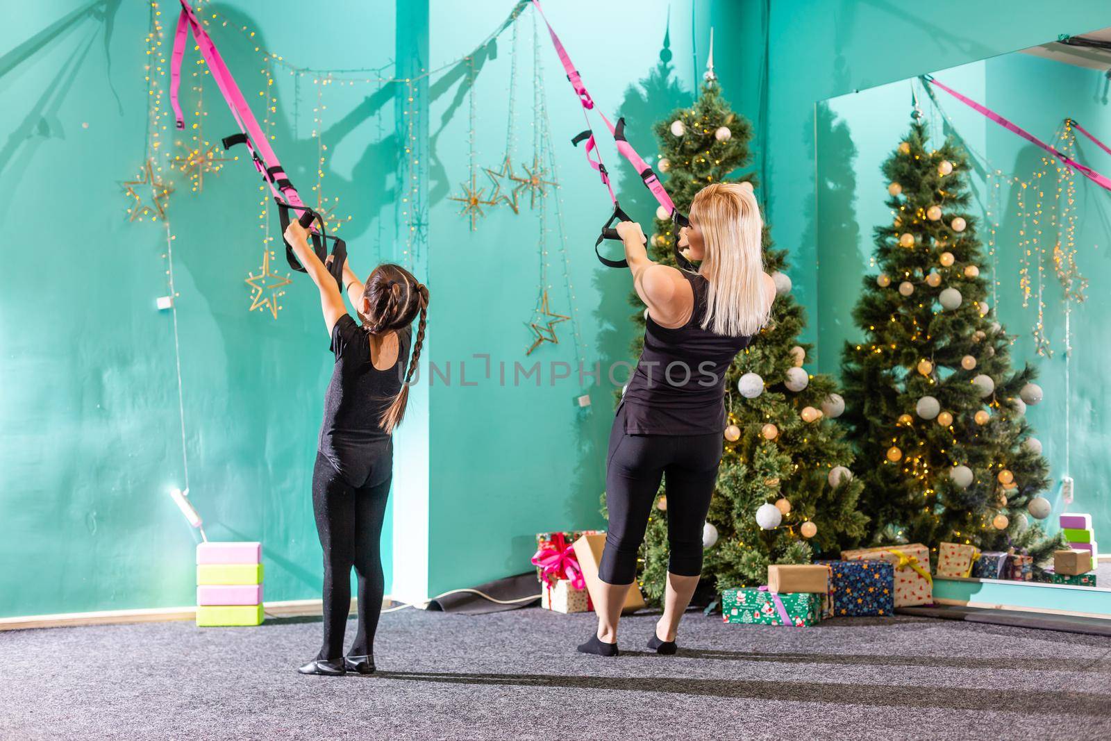 active mother and daughter doing fitness near the christmas tree