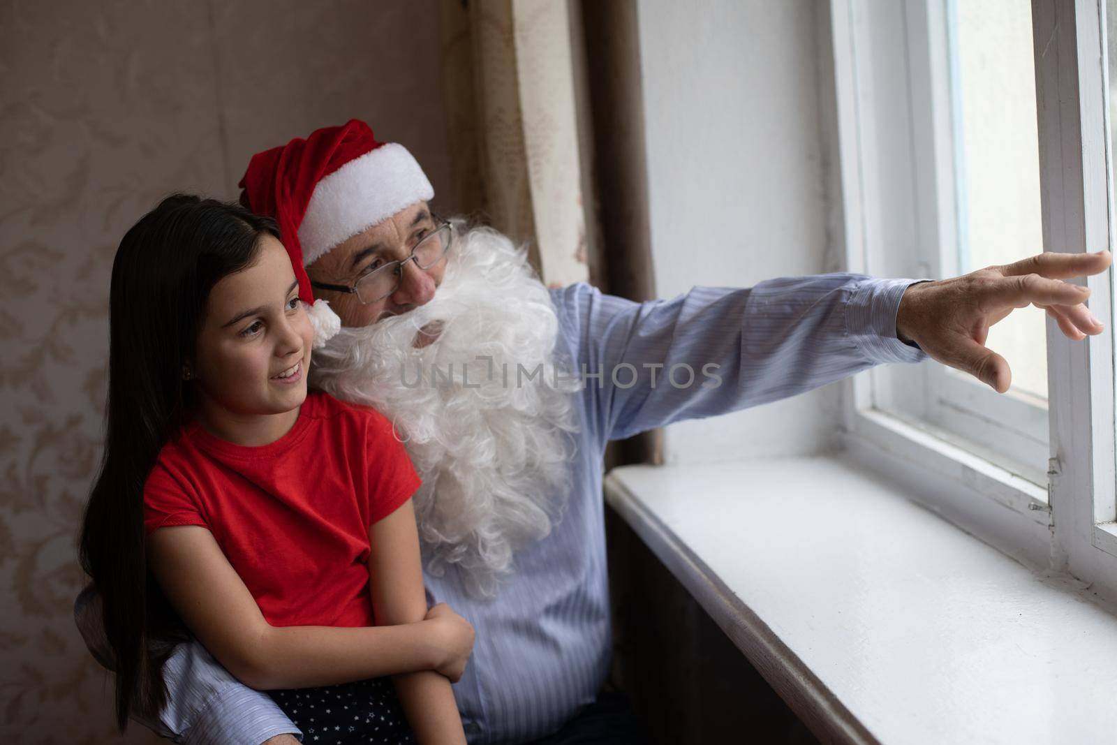 Picture of an elderly man wearing a Santa hat while playing with his grandchildren
